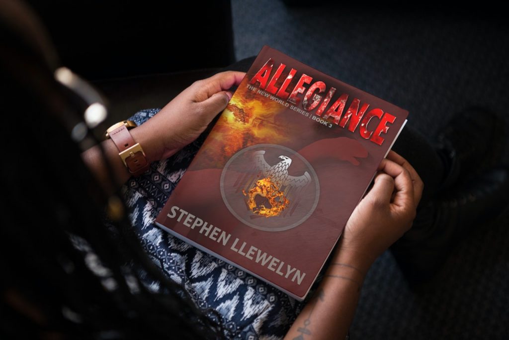 A woman holding a copy of ALLEGIANCE by Stephen Lllewelyn